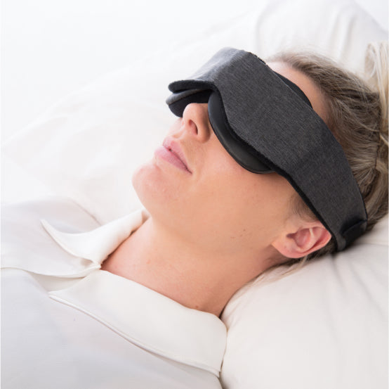 woman with head on pillow wearing a blackout sleep mask